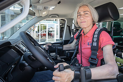 Frau mit Tetraplegie steuert ein Auto mit Joystick und Spezialsteuerung – individuelle Mobilitätslösung für Menschen mit Querschnittlähmung.