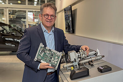Roland Arnold in einem Showroom, präsentiert stolz die elektronischen Komponenten des Space Drive Systems.