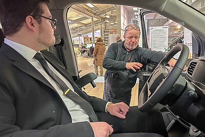 Ein Techniker erklärt einem Fahrer die Bedienung der PARAVAN Fahrhilfen in einem behindertengerecht umgebauten Fahrzeug.