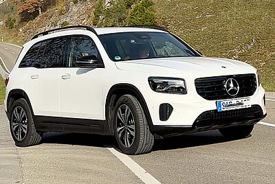 Ein weißer Mercedes GLB von vorne links schräg bei Sonnenschein Fotografiert.