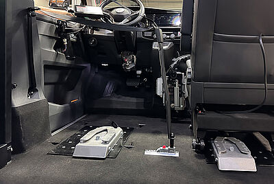 Der Innenraum eines behindertengerecht umgebauten Fahrzeugs ohne Fahrersitz, ausgestattet mit der PARAVAN Dockingstation. Dadurch können Rollstuhlfahrer direkt mit ihrem Rollstuhl bis zum Lenkrad vorfahren. Die Dockingstation fixiert den Rollstuhl sicher und ermöglicht selbstständiges Autofahren. 