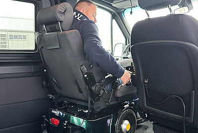 Innenansicht eines Fahrzeuges mit angepasstem Fahrersitz und Kopfstütze, Blick auf die Fahrerseite und Armaturen.