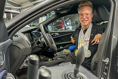 Ein zufriedener Nutzer fährt selbstständig Auto mit Joystick – gelebte Inklusion.