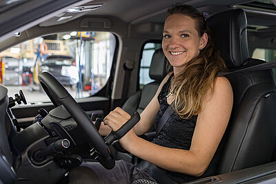 Frau mit Tetraplegie fährt Auto mit Handsteuerung – barrierefreies Autofahren dank individueller PARAVAN Fahrhilfen.