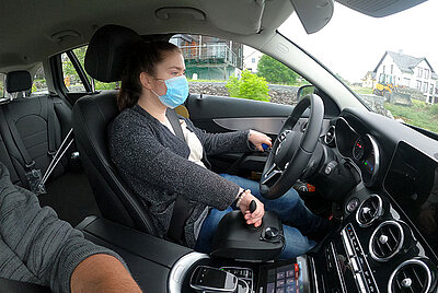a woman with mask in her face is driving a drivers school car in Aichelau