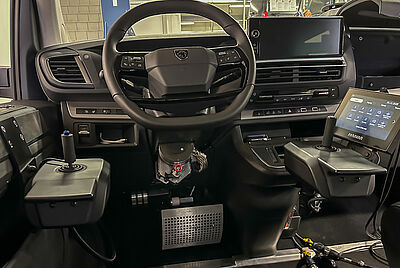 Der Innenraum eines Fahrzeugs, vorne beim Fahrersitz, bei dem links und rechts neben dem Lenkrad jeweils ein Joystick verbaut ist, mit denen man das Fahrzeug steuern kann. Am rechten Joystick befindet sich außerdem das PARAVAN Touchdisplay, über das man die Sekundärfunktionen steuern kann.