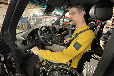 Mann mit Tetraplegie fährt Auto direkt aus dem Rollstuhl mit Handsteuerung und Spezialfahrhilfen.