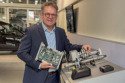 Roland Arnold in einem Showroom, präsentiert stolz die elektronischen Komponenten des Space Drive Systems.