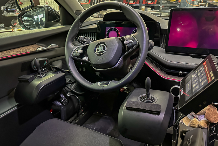 Links und rechts neben einem Autolenkrad befinden sich jeweils ein Joysticks verbaut. Am rechten Joystick befindet sich außerdem ein Paravan Touch Display. 