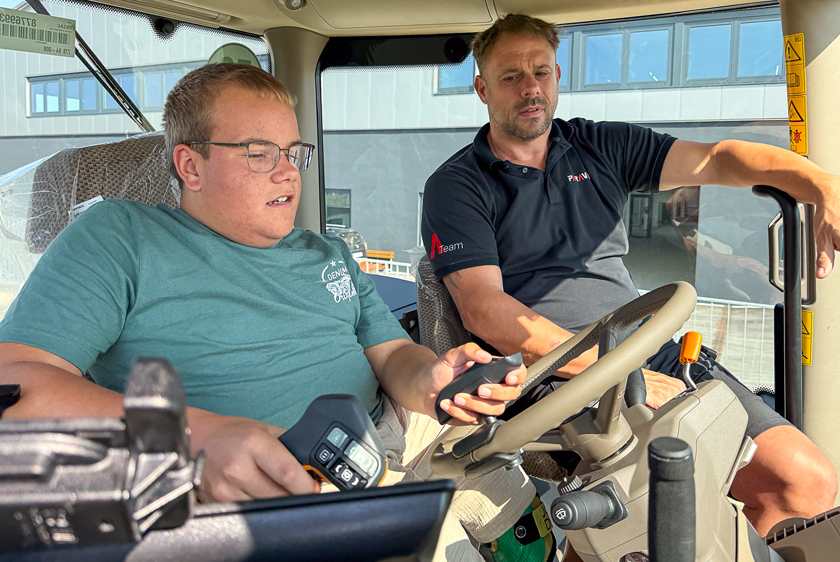 PARAVAN Mitarbeiter erklärt einem jungen Mann die angepasste Bedienung im Cockpit des John Deere Traktors.