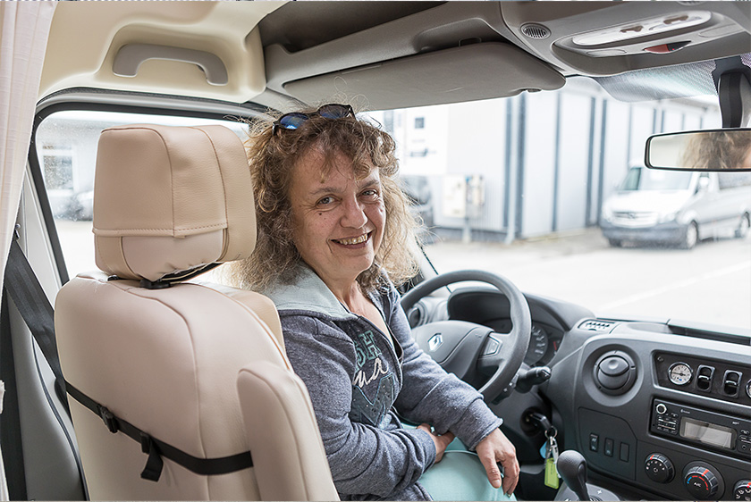 Doris Frey sitzt lächelnd am Steuer ihres individuell angepassten Fahrzeugs
