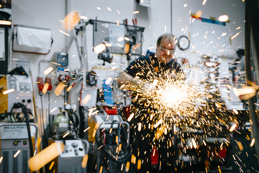PARAVAN Mitarbeiter bei Metallarbeiten in der Werkstatt, während zahlreiche Funken durch die Luft fliegen.